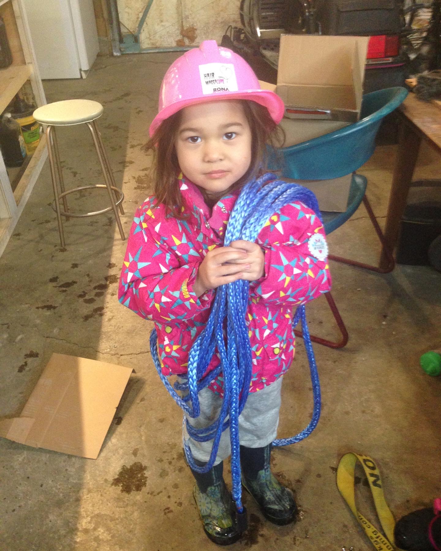 Young family member wearing a hard hat and holding climbing rope
